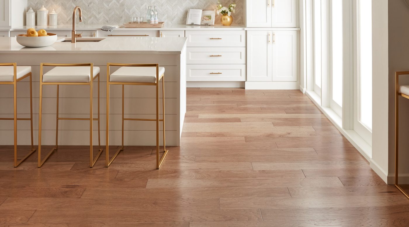 A wood plank floor laid through a bright kitchen with herringbone tile on the wall